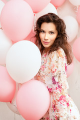 Beautiful young girl in dress with balloons on birthday. Portrait of cute woman with multicolored balloon. Cute brunette girl in the studio with balls filled © timofeev
