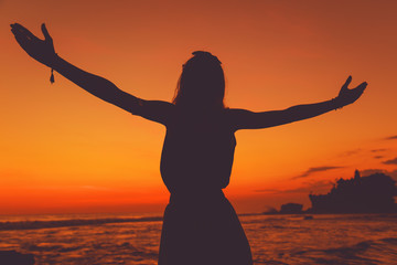 Girl with arms wide open enjoying sea / ocean scenery in Bali, Indonesia.