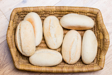 minibaguetter i en flätat korg ovanifrån på träbord