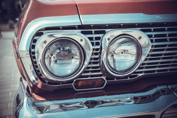 close up front view of old classic car headlight is outdoor with bokeh background