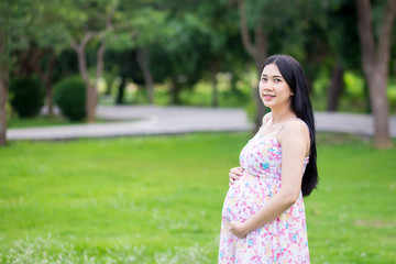 Naklejka premium Beautiful pregnant woman relaxing outside in the park