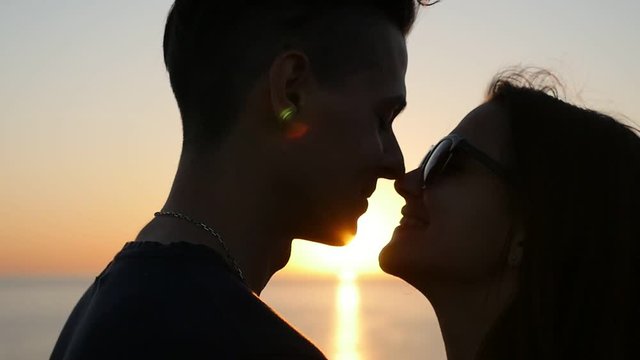 An amasing view of an enamored pair hugging each other and doing an Eskimo kiss at a picturesque sunset on the Black sea coast in summer
