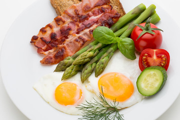 Fried eggs with bacon on the wooden table.