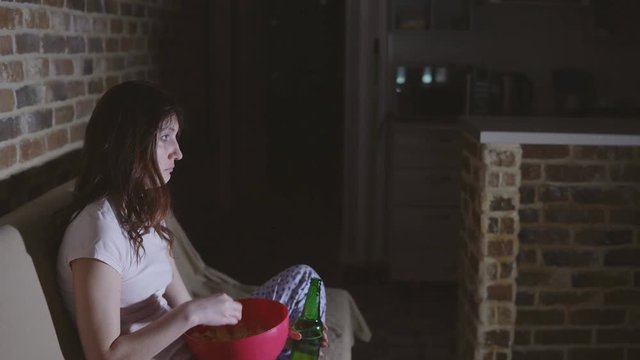 Young woman crying and drinking beer with chips.