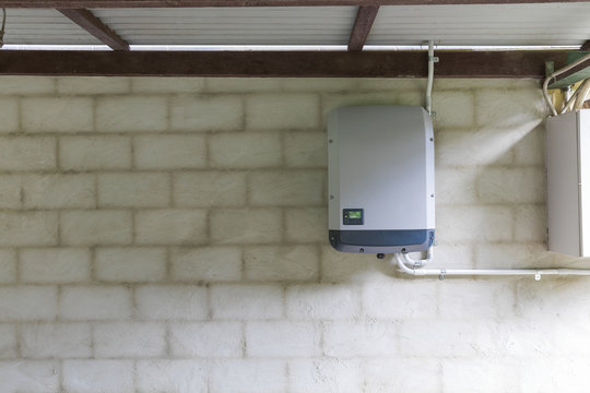 Solar power inverter mounted on brick wall inside garage