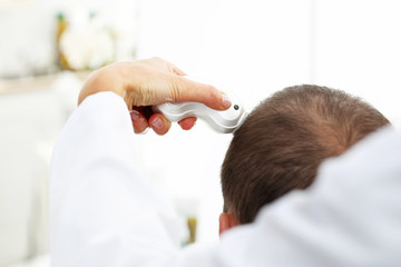 Łysienie. Głowa mężczyzny z przerzedzonymi włosami podczas badania skóry głowy i włosów...