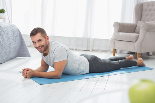 Sports workout. Delighted well built man lying on the floor while having a sports workout