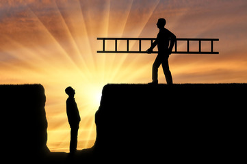 A silhouette of a man carries a ladder to another man who is in a pit