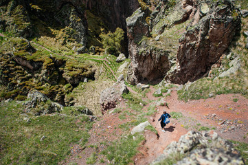 Active lifestyle. Travel, tourism and trekking. Woman tourist with a backpack and sticks descends into a mountain gorge.