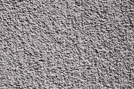A light lilac grey painted stone wall as texture of a background

