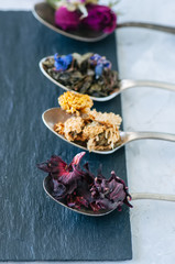 Obraz na płótnie Canvas Various flavors of tea. Green tea flower tea matcha karkade in spoons.