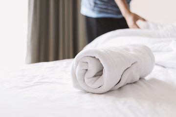 towel on white bed with a man making a bed