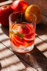 Refreshing blood orange water or infused water in a glass on a wooden background.