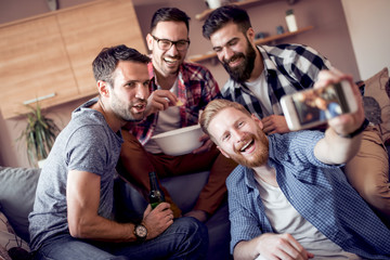 Happy male friends having great time at home