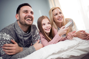 Happy family watching TV in bed