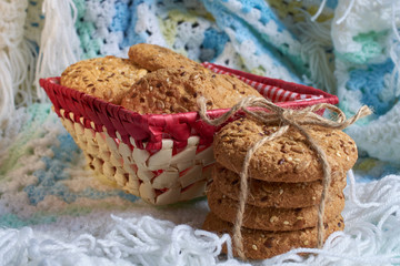 Fototapeta na wymiar homemade oat cookies with sunflower seeds in and near red checkered basket on white and blue plaid