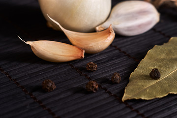 On the black style table, seasonings: onion, garlic, black pepper peas and bay leaf