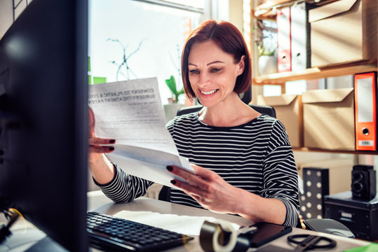 Business Woman Sitting At The Desk And Reading Mail At The Office