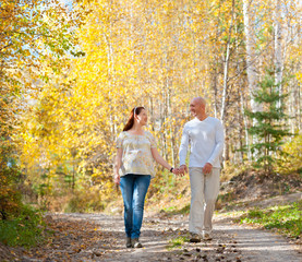 husband and wife walk in autumn forest