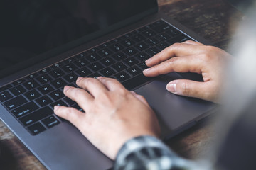 Closeup image of hands working and typing on laptop keyboard with blur background