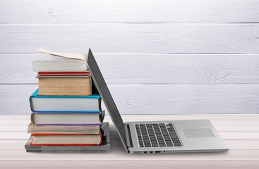 Stack of books with laptop on table