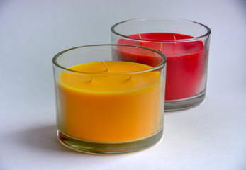 two candles (red and yellow) in transparent glasses.in the foreground yellow