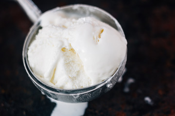 Fototapeta na wymiar Close view of ice cream scoop with white ice cream starting to melt in it.