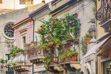 Fototapeta na wymiar balcony with red flower pots and green foliage