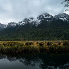 A stunning scene of the reflection of snow mountain and yellow grassland