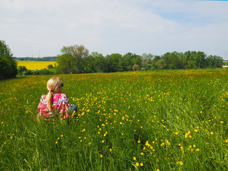 Fototapeta premium Frau sitzt auf einer Blumenwiese