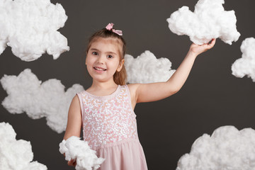 the girl touches the clouds and plays, shot in the studio on a gray background