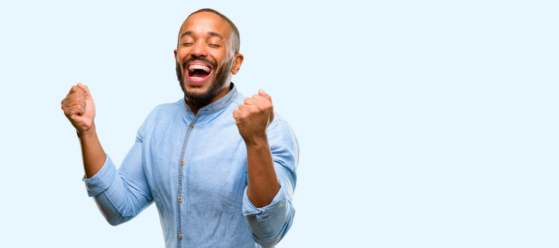 African american man with beard happy and surprised cheering expressing wow gesture isolated over blue background