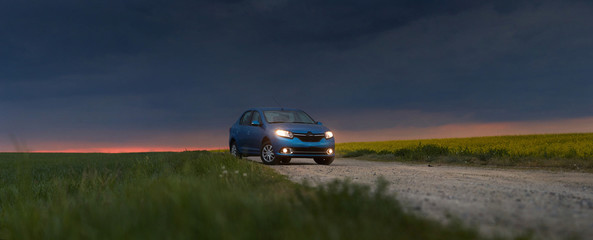 GOMEL, BELARUS - May 15, 2018: blue car parked in the field against a stormy sky.
