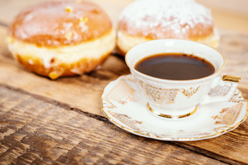 cup of delicious and fragrant coffee with a tasty donuts on a wooden table