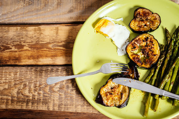 delicious dinner of asparagus fried eggs and courgette on a green plate on a wooden table