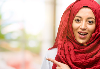 Young arab woman wearing hijab pointing away side with finger