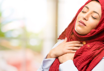 Young arab woman wearing hijab with hands in heart, expressing love and health concept
