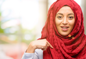 Young arab woman wearing hijab happy and surprised cheering expressing wow gesture pointing up