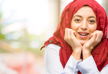 Young arab woman wearing hijab happy and surprised cheering expressing wow gesture