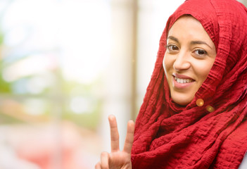 Young arab woman wearing hijab raising his fingers, number two