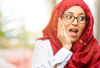 Young arab woman wearing hijab so happy and confident showing a big smile surprised finger