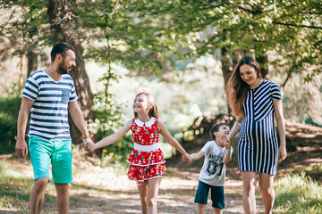 Fototapeta premium Happy family in the park.Pregnant mother with her family on vacation