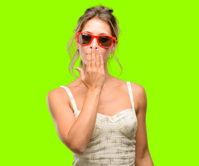 Young beautiful woman wearing red sunglasses covers mouth in shock, looks shy, expressing silence and mistake concepts, scared