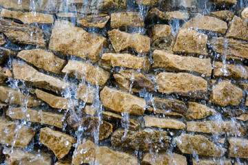 Waterfalls dripping and flowing down rock wall closeup.