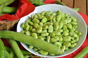 fave fresche ,sbucciate dentro ad un piatto, a fianco le fave con la buccia