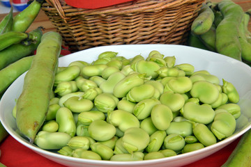 fave fresche ,sbucciate dentro ad un piatto, a fianco le fave con la buccia