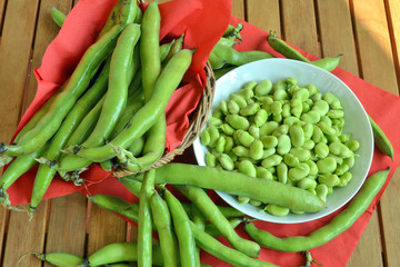 fave fresche ,sbucciate dentro ad un piatto, a fianco le fave con la buccia