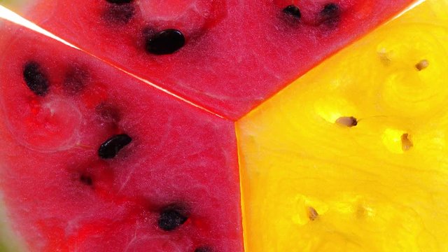 Super closeup flat-lay view of three slices of red and yellow watermelon rotating in 4K. Refreshing and juicy healthy fruit.
