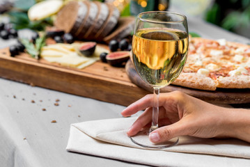 Female hand with glass of wine,pizza in background
