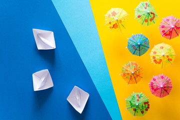 Overhead view on beach with umbrellas and sea with boats. Sea travel and summer vacation minimal concept. Paper origami composition. Flat lay. Top view. Copy space